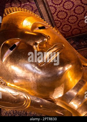 Eine atemberaubende Nahaufnahme des Kopfes des goldenen liegenden Buddha im Wat Pho Tempel in Bangkok, Thailand. Die komplizierten Details des ruhigen fa des Buddha Stockfoto