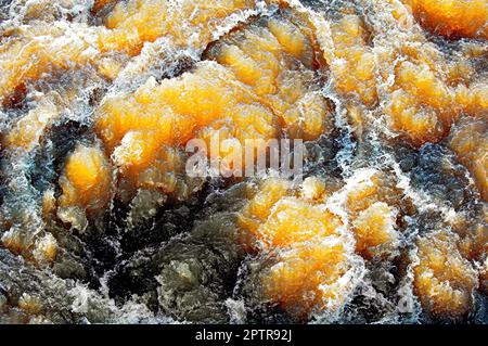 Das schräge Sonnenlicht scheint durch das sprudelnde Wasser eines Flusses mit Stromschnellen Stockfoto