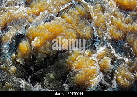 Das schräge Sonnenlicht scheint durch das sprudelnde Wasser eines Flusses mit Stromschnellen Stockfoto