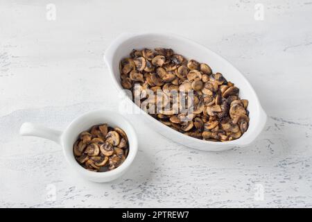 Gebratene Champignon-Pilze in gefetteter Form auf hellgrauem Hintergrund, Draufsicht. Ich koche einen vegetarischen Auflauf Stockfoto
