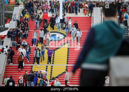 Leipzig, Deutschland. 28. April 2023. Besucher gehen am zweiten Tag der Messe die Treppe mit dem Leipzig Book Fair Logo in der Glashalle hinauf. Nach einer dreijährigen Zwangsunterbrechung findet die Buchmesse vom 27. Bis 30. April wieder statt. Auf dem Frühjahrstreffen der Buchindustrie werden rund 2.000 Aussteller aus 40 Ländern ihre buchbezogenen Innovationen vorstellen. Österreich wird das Gastland auf der Buchmesse sein. Kredit: Jan Woitas/dpa/Alamy Live News Stockfoto