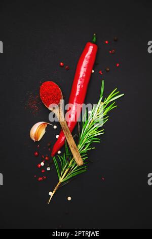 Paprika, Chili-Pfeffer, Knoblauch und Rosmarin auf dunklem Hintergrund. Essenshintergrund, Stillleben, Draufsicht. Stockfoto