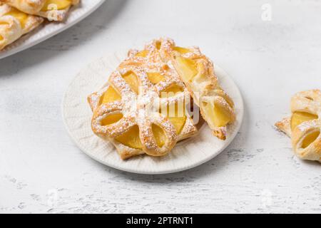 Gebackene Ananas in Blätterteig mit Puderzucker auf hellblauem Hintergrund, Draufsicht. Köstliche hausgemachte Puffs Stockfoto