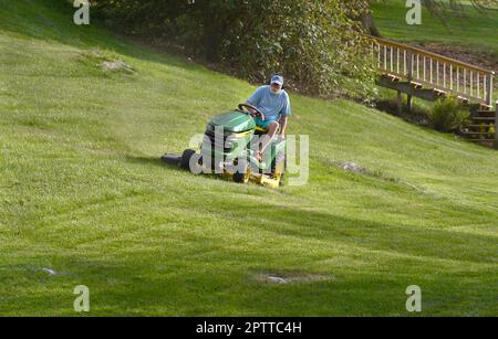 Ein Mann mäht seinen Rasen mit einem John Deere Aufsitzmäher in Abingdon, Virginia, USA Stockfoto