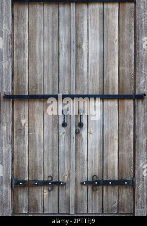 Die Textur eines antiken hölzernen Tür aus dem 16. und 17. Jahrhundert. Alte Tore aus Holz mit Metall geschmiedet Fragmente verstärkt Stockfoto
