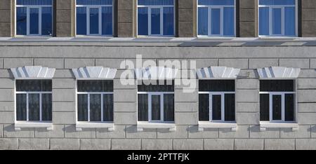 Textur einer verglasten modernen Windows von einem Gebäude aus grauem Beton. Nahaufnahme einer Betonwand mit Kunststofffenster Stockfoto