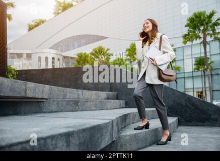 Die Geschäftsfrau, die in der Stadt die Treppe hoch stieg, hielt einen Laptop und sprach ein Mobiltelefon. Sie beeilte sich, die Treppe zu betreten, zur Hauptverkehrszeit, um im Büro zu arbeiten Stockfoto