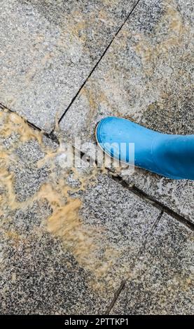 Ein lockerer Kopfsteinpflaster spritzt auf einen Kinderstiefel, wenn er darauf tritt. High-Speed-Aufnahmen Stockfoto