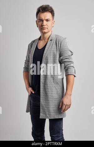 Porträt eines gutaussehenden Mannes mit Wolljacke, schwarzem Hemd und Jeans. Stockfoto