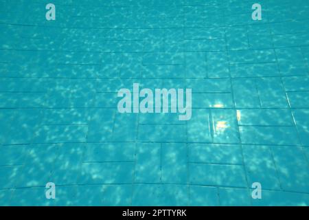 Schwimmbad unten, Sonne am blauen Kacheln, Linien durch Wasser Lichtbrechung verzerrt. Stockfoto
