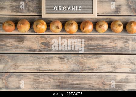 Lebensmittelzusammensetzung aus Zwiebelzwiebeln, kühlem Pfeffer, Äpfeln und Tomaten, Kartoffeln auf Regalen mit Namensschild Bio. Bio-Lebensmittel und frische Vitaminmahlzeit in Stockfoto