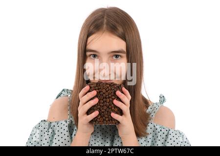 Ein junges, hübsches Mädchen in einem gepunkteten Kleid mit einer Tasse Kaffee, isoliert auf weißem Hintergrund. Die Tasse besteht aus Kaffeebohnen. Hochauflösendes Pho Stockfoto