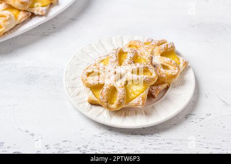 Gebackene Ananas in Blätterteig mit Puderzucker auf hellblauem Hintergrund, Draufsicht. Köstliche hausgemachte Puffs Stockfoto