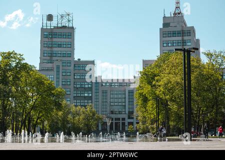 Derzhprom-Gebäude mit Brunnen und grünem Park im Frühling auf dem Freedom Square in Charkiv, Ukraine. Konstruktivistische Architekturdetails Stockfoto