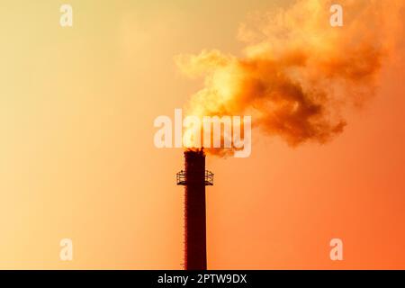 Weltverschmutzungskonzept. Fabrikschornstein bläst Rauch aus Rohren im Hintergrund des Abendhimmels Stockfoto
