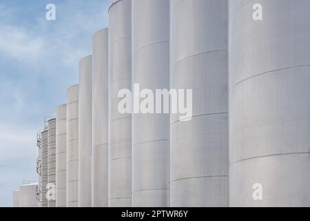 Eine Reihe von Stahlweintanks für die Weingärung in einem modernen Weingut. Große Brauereisilos, die üblicherweise zur Lagerung von Gerste oder fermentiertem Bier gegen blu verwendet werden Stockfoto