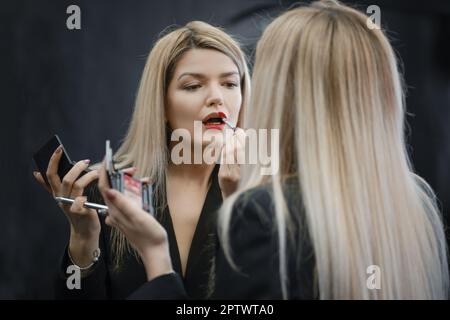 Frau, die flüssigen Lippenstift auf den Spiegel suchen Stockfoto