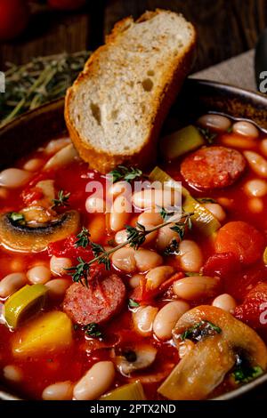 Rustikale Bohnensuppe mit Kartoffeln und Würstchen Stockfoto