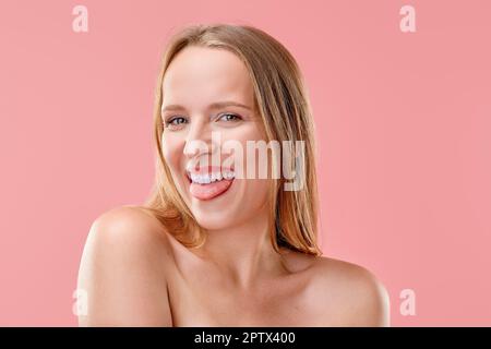 Das lustige Mädchen schaut geradeaus und zeigt ihre Zunge. Stockfoto