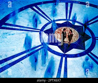 Der hohe Blickwinkel des jungen Mannes und der jungen Frau im belebten Innenhofsaal. Stockfoto