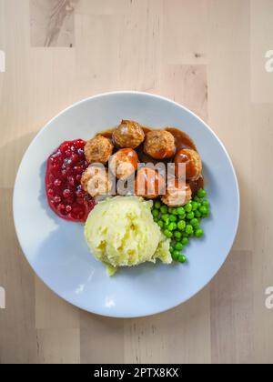 Traditionelles schwedisches Gericht: Fleischbällchen mit Preiselbeersauce, Kartoffelpüree und grünen Erbsen. Stockfoto