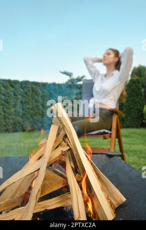 Das Feuer bricht im Grill aus (verschwommene junge Frau auf dem Hintergrund) Stockfoto