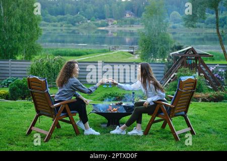 Glückliche Frauen, die draußen Weißwein toasten Stockfoto
