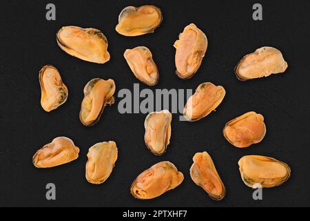 Gekochte und geschälte Muscheln, isoliert auf schwarzem Hintergrund Stockfoto