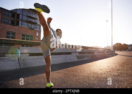 High-Kick für Exzellenz. Ein junger Kämpfer in Sportbekleidung, der einen hohen Kick gibt Stockfoto