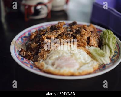 Gebratenes Schweinefleisch mit Knoblauch, Pfeffer und Spiegelei auf Reis. Stockfoto