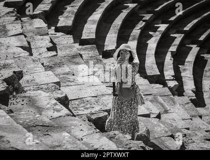 Eine vietnamesische Asiatin macht ein Foto mit ihrem Mobiltelefon, während sie das große römische Amphitheater in Side in der Provinz Antalya, Türkei (Tur Stockfoto