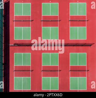 Blick von oben auf eine Pickleball-Anlage mit roten und grünen Plätzen in einem Vorstadtpark im Frühling. Stockfoto