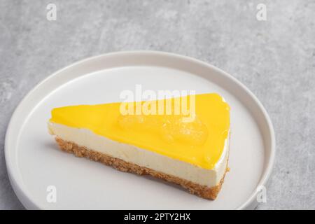 Dreieckiger Käsekuchen mit Zitrone auf einem weißen Teller Stockfoto