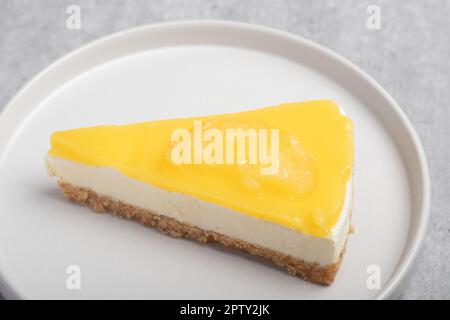 Dreieckiger Käsekuchen mit Zitrone auf einem weißen Teller Stockfoto