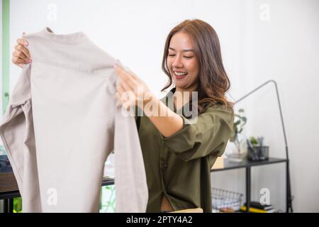 Glückliche asiatische Frau Kunde Öffnung Box und suchen eine neue Kleidung sie mag es sehr, aufgeregt Lächeln weibliche Shopper Auboxen Karton Paket, s Stockfoto