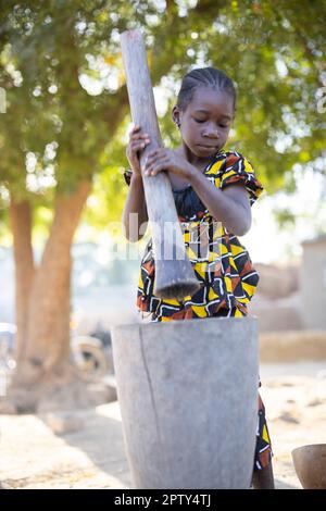 Ein junges Mädchen mahlt Hirsemehl mit Mörser und Stößel in der Region Segou, Mali, Westafrika. 2022 Dürre und Hungerkrise in Mali. Stockfoto