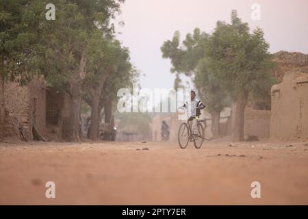 Ein Kind fährt mit dem Fahrrad durch die staubigen Dorfstraßen der Region Segou, Mali, Westafrika. 2022 Dürre und Hungerkrise in Mali. Stockfoto