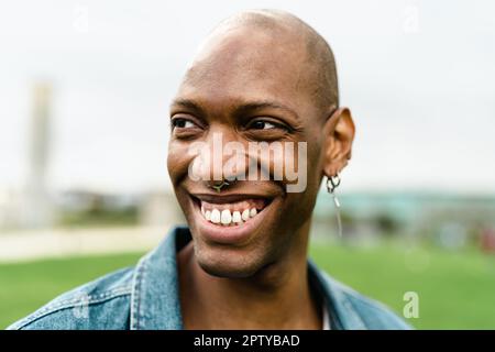 Fröhlicher afrikanischer Schwuler, der vor der Kamera posiert und lächelt Stockfoto