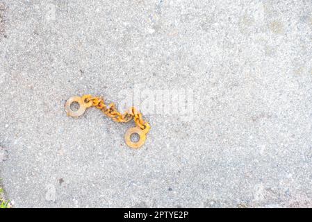 Draufsicht einer rostigen Kette auf einer Steinoberfläche. Dorf, Hütte, Garten. Stockfoto