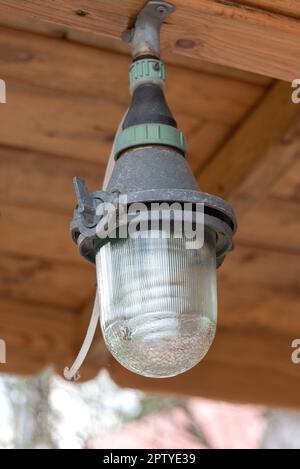 Die versiegelte Straßenlampe in einem Metallgehäuse ist an der Decke angeschraubt. Ländlich, Garten, Land. Stockfoto