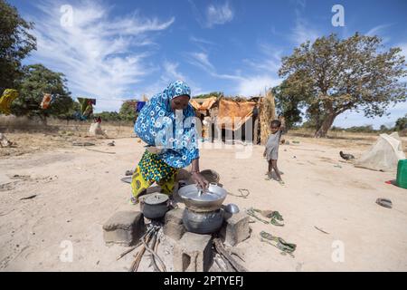 Mutter kocht eine Mahlzeit am offenen Kamin vor dem Haus der Familie in Segou Region, Mali, Westafrika. 2022 Dürre und Hungerkrise in Mali. Stockfoto