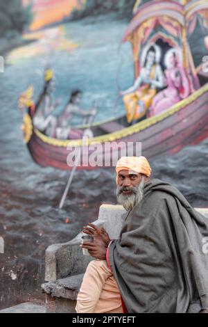 Indien, Uttarakhand, Rishikesh, Sadhu, heiliger Mann, Vor dem Wandgemälde. Stockfoto