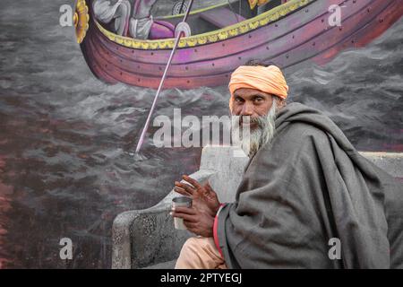 Indien, Uttarakhand, Rishikesh, Sadhu, heiliger Mann, Vor dem Wandgemälde. Stockfoto