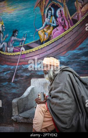 Indien, Uttarakhand, Rishikesh, Sadhu, heiliger Mann, Vor dem Wandgemälde. Stockfoto