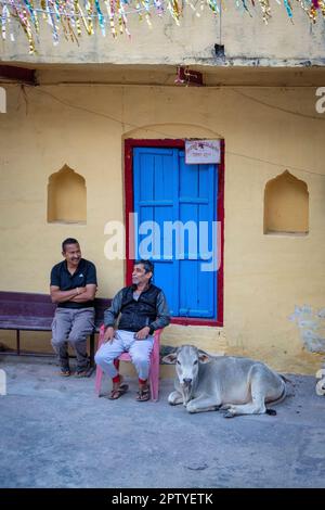 Indien, Uttarakhand, Rishikesh, zwei Männer vor dem Haus. Junge Kuh, Kalb. Stockfoto