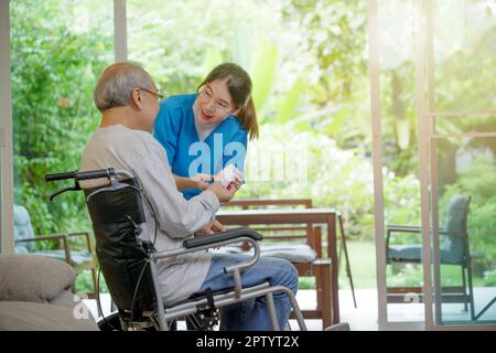 Asiatische junge Frau Krankenschwester Pillen mit Hilfe verschreibt Medizin zu älteren behinderten Patienten auf Rollstuhl, wenn ältere ältere ältere Mann Patienten die Zeit, nach Hause zu gehen Stockfoto