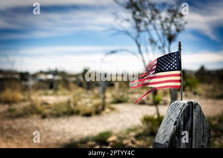 Eine zerschlissene amerikanische Flagge, die an einem Grabmal in Boothill in Tombstone, Arizona, befestigt ist. Stockfoto