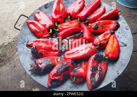 Rösten Sie köstliche rote Paprika für einen rauchigen Geschmack und schnelles Schälen. Balkansalatrezepte. Thermische Verarbeitung der Pfefferpflanze auf einem Metallkreis. Pe Stockfoto