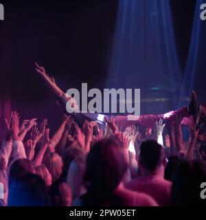 Getragen von einer unglaublichen Menge. Ein Bühnentaucher, der auf einem Rockkonzert durch das Publikum getragen wird Stockfoto