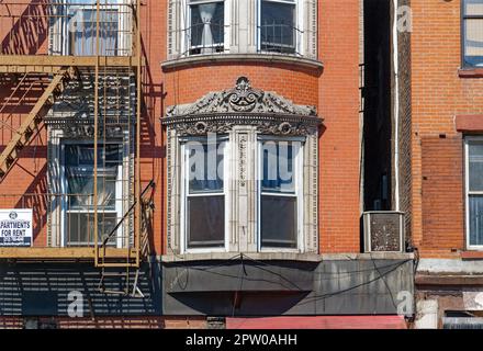 Kunstvoll verzierte Terrakotta-Spandrels und Fenster zieren dieses mittelhohe Apartment-Gebäude aus rotem Backstein in der Lower East Side von New York City. Stockfoto